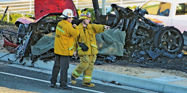 Sheriff's deputies work near the wreckage of a Porsche that crashed into a light pole on Hercules Street near Kelly Johnson Parkway in California, killing actor Paul Walker. Photo / AP