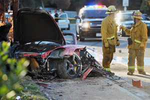 First responders gather evidence near the wreckage of the wrecked Porsche sports car. Photo / AP / The Santa Clarita Valley Signal, Dan Watson