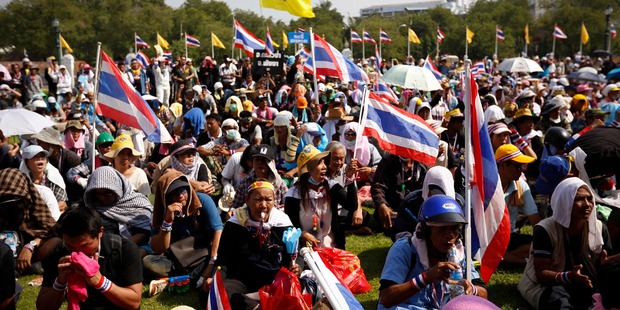 Anti-government protesters wave Thai national flags and yellow flags with an emblem of the Thai king as they listen to leaders speaking at Government House in Bangkok. Photo / AP