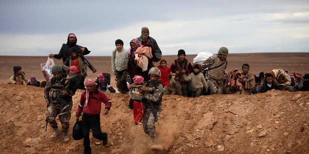 Syrian refugees cross the Jordan border yesterday, aided by soldiers from the Jordanian army. Photo / AP