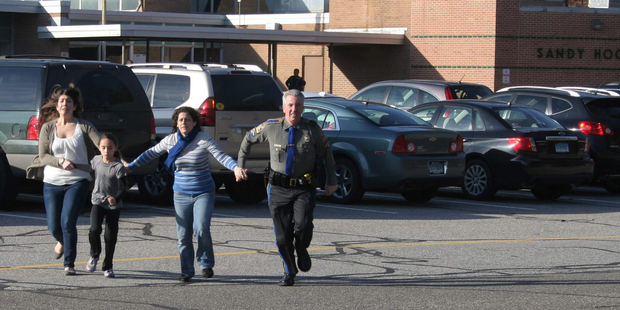 A police officer leads two women and a child away from Sandy Hook Elementary School in Newtown. Photo / AP