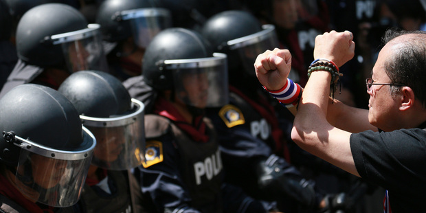 An anti-government protester crosses his arms in front of riot police as a gesture of his opposition to the government outside the headquarters of Prime Minister. Photo / AP
