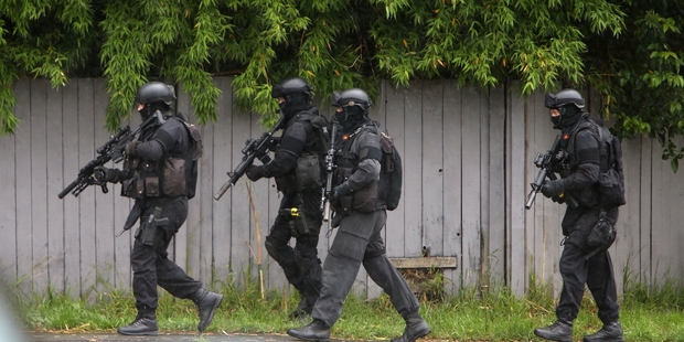 Members of the armed offenders' squad head towards a Whangarei house after a family violence incident where a man was thought to have firearms. Photo/Michael Cunningham.