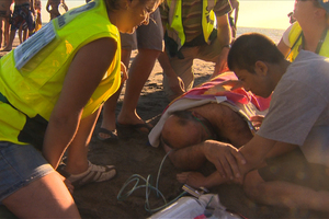 Surf rescue attend to a group of people on the beach at Piha after they had to be pulled from dangerous conditions. Photo / Piha Rescue