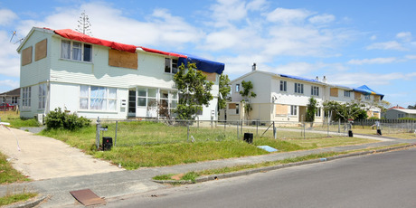 In Wallingford Way, Hobsonville, hundreds of windows remain boarded up and roofs are covered with tarpaulins or tied down with ropes. Photo / Chris Gorman