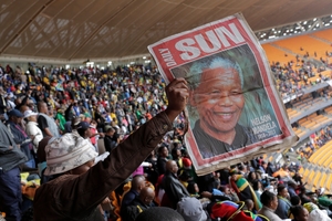 A man holds up an image of former South African president Nelson Mandela at the memorial service at the stadium in Soweto. Photo / AP