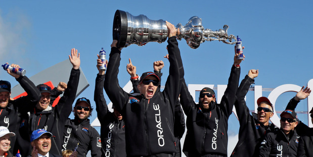 Oracle Team USA skipper Jimmy Spithill holds up the Auld Mug as they celebrate in the podium after winning the America's Cup over Emirates Team NZ. Photo / AP