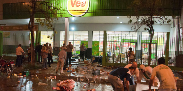 Employees of a supermarket try to recover items left behind by looters after the store was looted in San Miguel de Tucuman, Argentina. Photo / AP