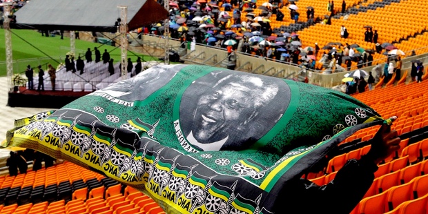 A man covers himself from the rain as he arrives for the memorial service for former South African president Nelson Mandela at the FNB Stadium in Soweto, near Johannesburg. Photo /AP