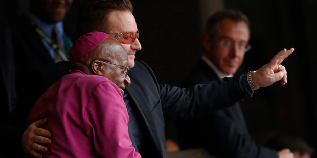 Retired Anglican Archbishop Desmond Tutu and musician Bono wave to mourners during the memorial service for former South African president Nelson Mandela. Photo / AP