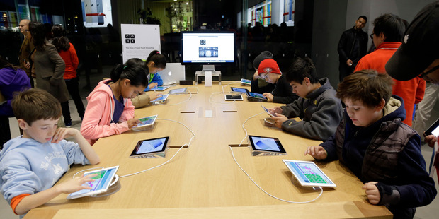 Children build code using iPads at a workshop in California this month. Apple has a lot of happy customers, and according to a labour advocacy group, conditions for its Chinese workers are improving. Photo / AP