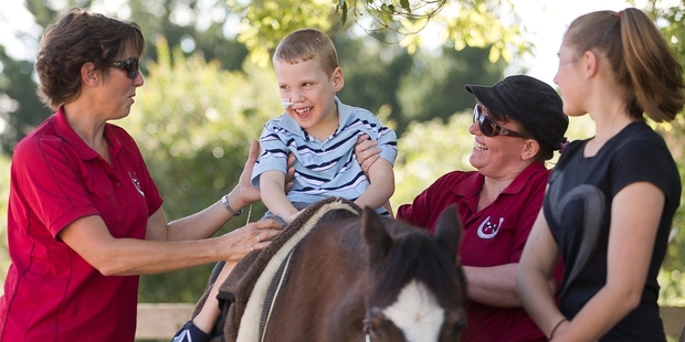 Children such as Jordan, who has cerebral palsy, enjoy their time riding. He is helped by Alison Green (left), Alison Daldy and Molly Green. Photo / Greg Bowker