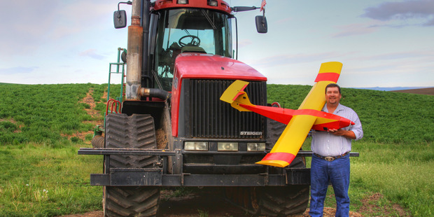 Farmer Robert Blair stands in front of his tractor holding an unmanned aircraft that he built in Kendrick, Idaho. Photo / AP