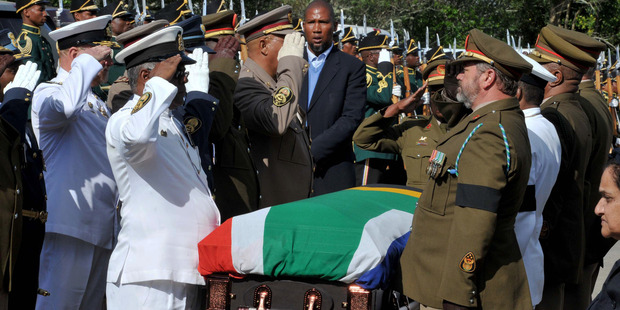 Military officers salute as Mandela's grandson Mandla Mandela watches over the casket as it arrives at the Mandela residence in Qunu, South Africa. Photo / AP