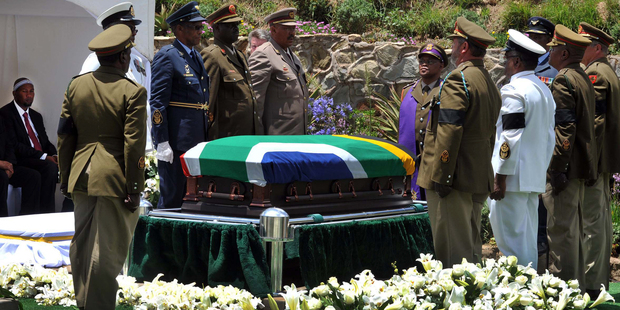 Nelson Mandela's grandson Mandla Mandela, left, watches as military soldiers stand at attention over former South African President Madela's casket before his burial. Photo / AP