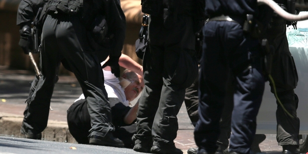 Armed police subdue Abdula Ganiji after they had rushed his car and dragged him out outside the New South Wales state Parliament in central Sydney. Photo / AP