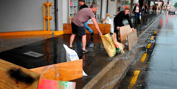 Cafe LOL owner Paul Martin and Wall Street manager Regan Bennett put out sandbags and boards in St Andrew St to prevent water from flowing into the mall. Photo / Craig Baxter