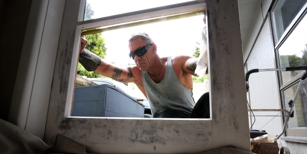 DAMAGE: Glazier Chris Kingan repairs a door broken by thieves who burgled a Whangarei home on Christmas Day then returned to kick their way through another door on Boxing Day. PHOTO/JOHN STONE