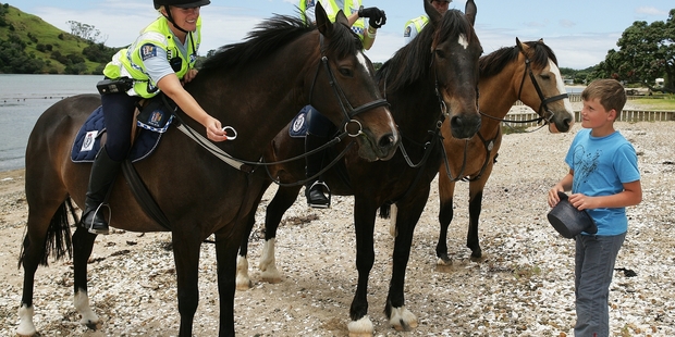 SADDLING UP: Braedyn McLachlan being offered a wristband by Constable Claire Carter at Pataua South yesterday as Whangarei police started patrolling the district's beaches on horseback. PHOTO/RON BURGIN