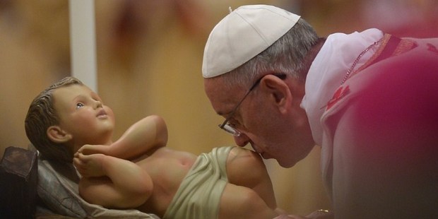 Pope Francis kisses the unveiled baby Jesus during a Christmas Eve mass at St Peter's Basilica. Photo / AFP
