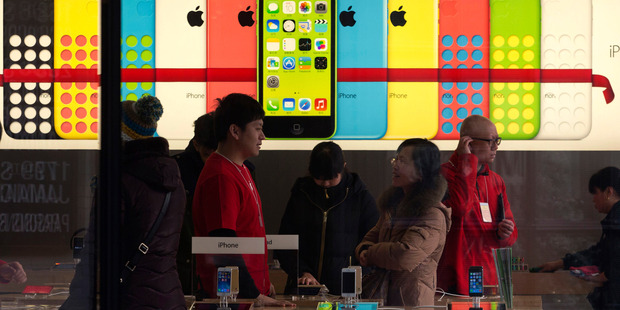 A woman talks to a salesperson in front of an advertisement for iPhones at Apple's retail store in Beijing Monday, Dec. 16, 2013. Photo / AP