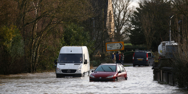A van and a car stuck in a flooded road near Reigate, England. Photo / AP