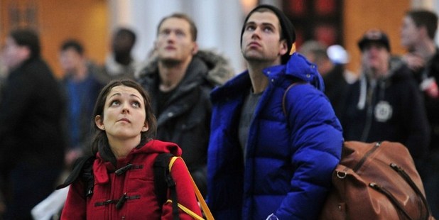 Passengers look at departure boards as they wait for trains at Kings Cross Station in central London. Photo / AFP