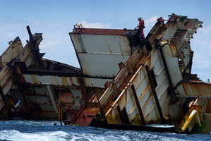 A workman is using a cutting torch on the wreck of the MV Rena. Photo / Alan Gibson