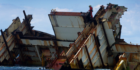 A workman is using a cutting torch on the wreck of the MV Rena. Photo / Alan Gibson