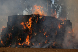 The hay stack is being pulled apart by contractors and will take hours to contain. Photo / Ashburton Guardian