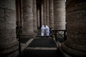 Two nuns walk under the Bernini colonnade at the Vatican, where cardinals will gather as early as this week to elect a new Pope. Photo / AP