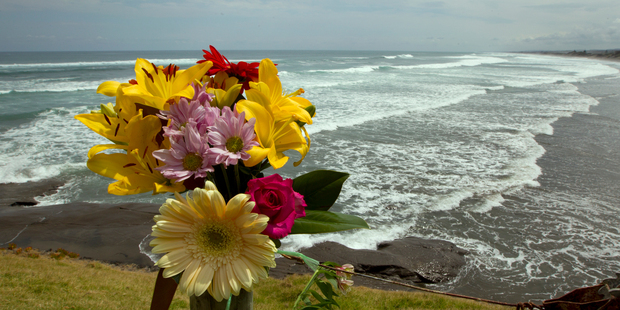 A flower tribute sits on a fence post as a memorial for Muriwai local Adam Strange. Photo / Brett Phibbs