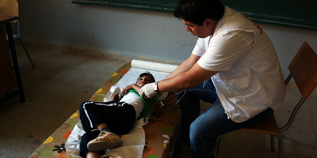 A doctor with Doctors Without Borders/Médecins Sans Frontières (MSF) examines a Syrian boy from a refugee camp for Syrians who have fled the fighting. Photo / AP