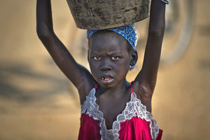 A young displaced girl carries a bucket of water back to her makeshift shelter at a UN compound which has become home to thousands of people displaced by the recent fighting. Photo / AP