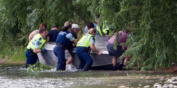 Police and survivors recover a jetboat that crashed, killing one and injuring four others. Photo / John Cowpland