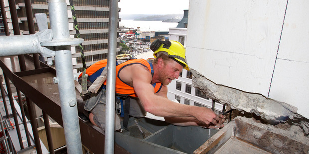Builder Michael Cameron perched on a bean while securing reinforcing during refurbishing work in the former Defence House building in Wellington. Photo / Mark Mitchell