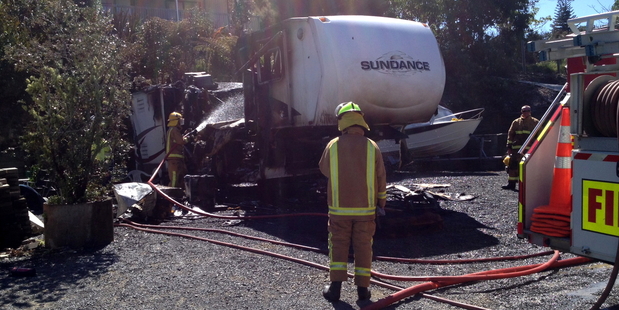 Russell firefighters dampen down what's left of the trailer home. PHOTO / SUPPLIED