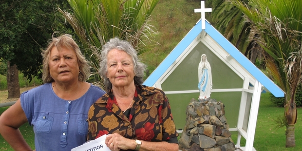 Parishioners Maata Job Rakena, left, and Jeanette Kinneally with a 400-signature petition calling on the Marist order to keep its nuns in Waitaruke. Behind them is Waitaruke's statue of Our Lady of Lourdes. Photo/Peter de Graaf