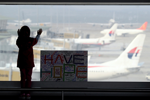 A girl stands next to a sign board made and written by the public at Kuala Lumpur International Airport. Photo / AP