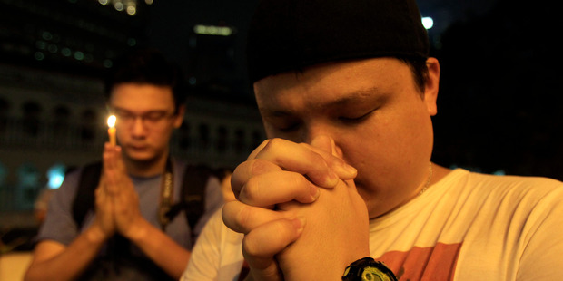 Men offer prayers during a candlelight vigil for passengers aboard a missing Malaysia Airlines plane. Photo / AP
