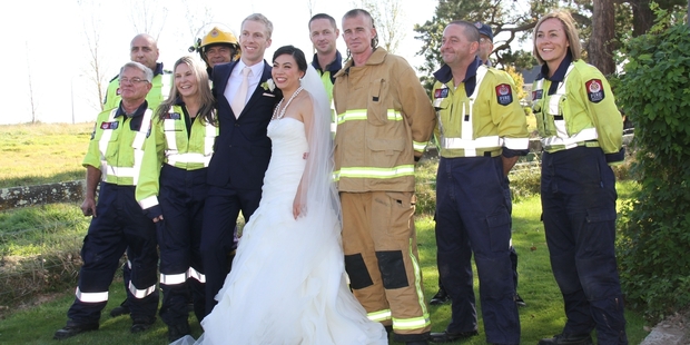 THANK YOU: Volunteer fire crew, mainly from Featherston fire station, surround Wellington newlyweds Tom Knobloch and Micaela Yee at the Brackenridge Country Retreat and Spa near Martinborough. The crew, plus others from Martinborough and Carterton, were called out to battle a tree and scrub fire on the estate's southern boundary.PHOTOS/ANDREW BONALLACK WTA080314ABFIRE02