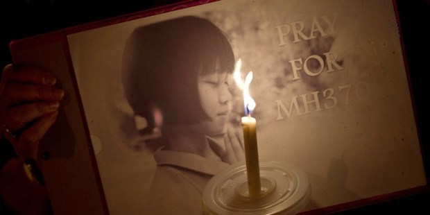 A Malaysian ethnic Chinese woman holds a placard as she takes part in a vigil for missing Malaysia Airlines passengers in KL. Photo / AFP