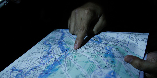 Capt. Syukri of the Malaysian Air Forces shows the flight path on a map during a search and rescue mission flight for the missing jet. Photo / Getty Images