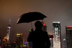 A man stands near an office building with lights forming the words MH370, the flight number of the missing Malaysia Airlines plane in Shanghai, China. Photo / AP