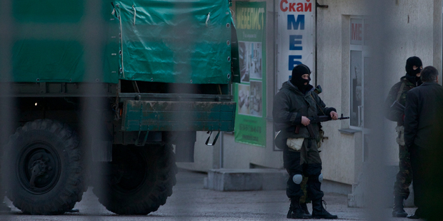 Unidentified armed men stand around before being loaded into a truck at a territory close to an Ukrainian military unit in Simferopol, Crimea. Photo / AP