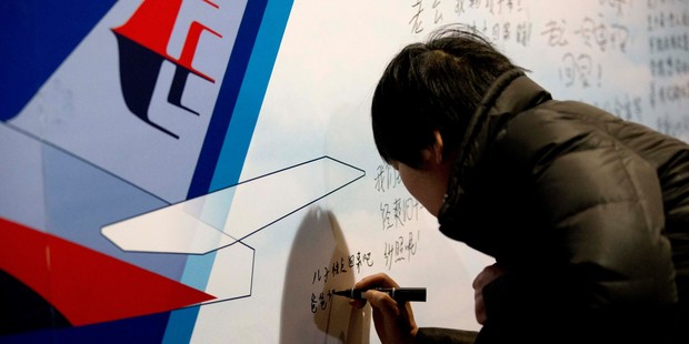 A woman writes a message on a board dedicated to the passengers aboard the missing Malaysia Airlines Flight MH370. Photo / AP
