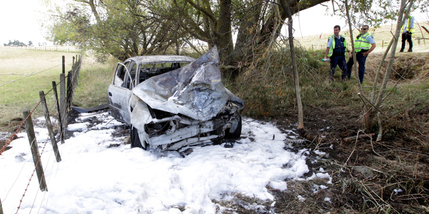 Police at the scene of yesterday's fiery crash near Waipukurau after fire crews had doused the wreck. Photo/Paul Taylor