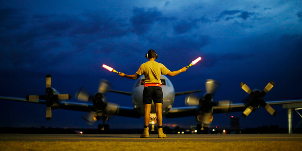 A ground controller guides a Royal Australian Air Force AP-3C Orion on the tarmac upon its return from a search for Malaysian Airlines flight MH370. Photo / Getty Images