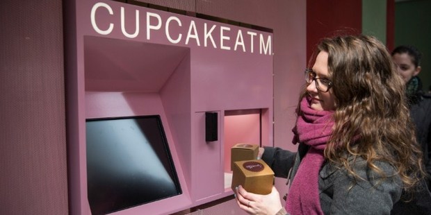 A woman takes her order of cupcakes after using a Cupcake ATM created by Sprinkles bakery in New York City. Photo / AFP