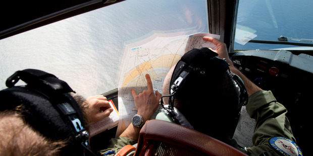 Flight Lt. Jayson Nichols looks at a map as he flies aboard a Royal Australian Air Force AP-3C Orion aircraft. Photo / AP / Michael Martina